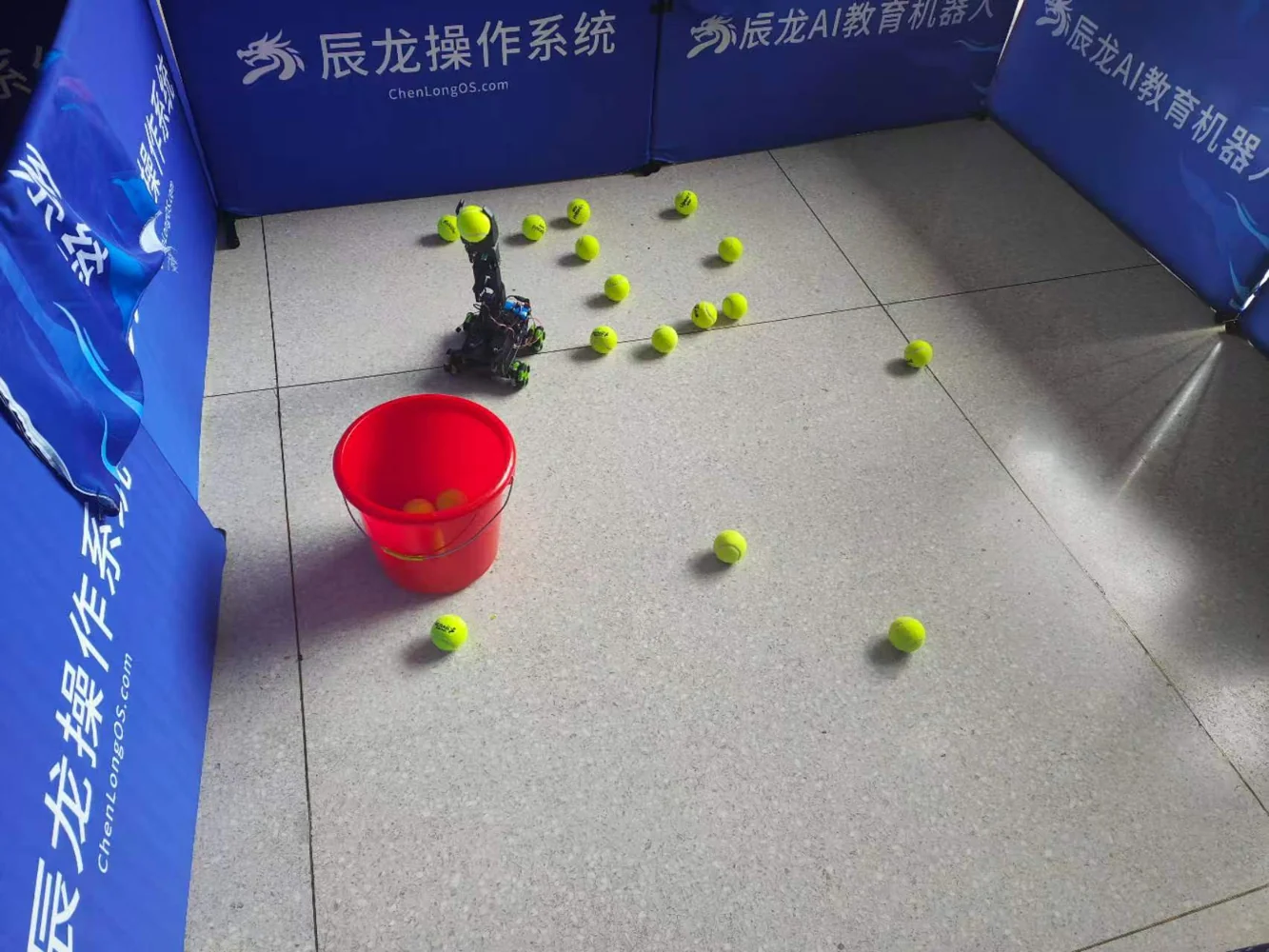 Our tennis-ball retrieval robot holding a ball on the actual operating-system competition floor, beside the collection bucket.